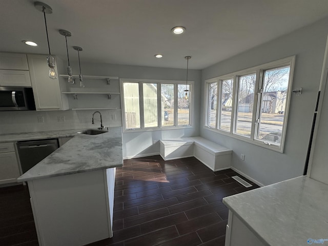 kitchen with stainless steel microwave, decorative backsplash, wood tiled floor, a sink, and dishwasher