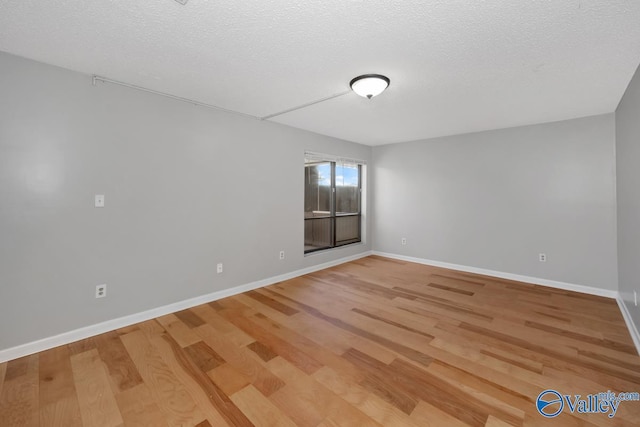 empty room with light wood-type flooring and a textured ceiling