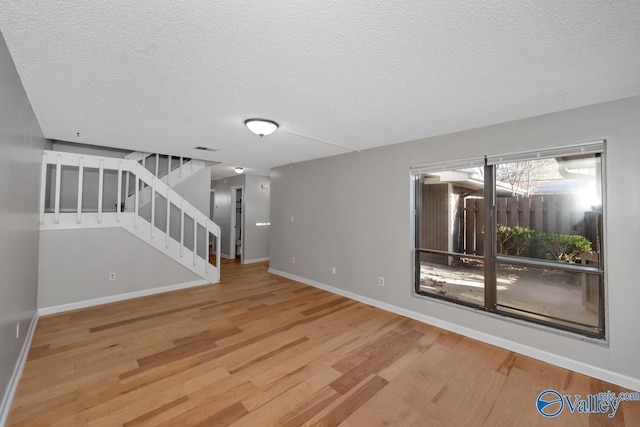 unfurnished living room featuring wood-type flooring and a textured ceiling