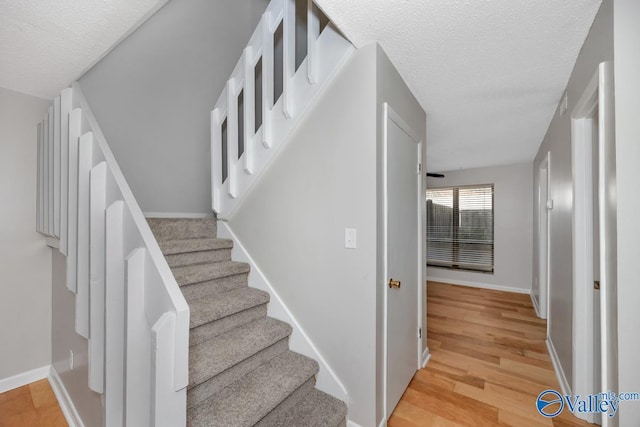 stairway featuring hardwood / wood-style floors and a textured ceiling