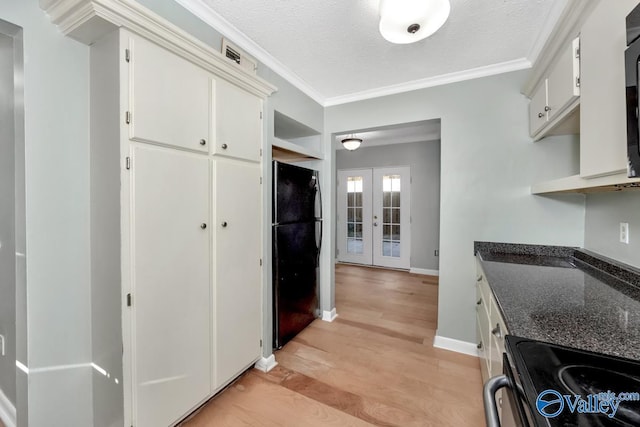 kitchen with white cabinetry, french doors, black fridge, a textured ceiling, and range