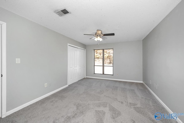 spare room featuring ceiling fan, light colored carpet, and a textured ceiling