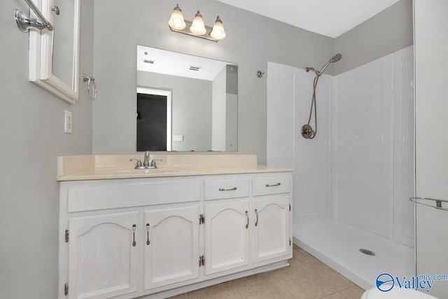 bathroom featuring tile patterned flooring, vanity, and a shower