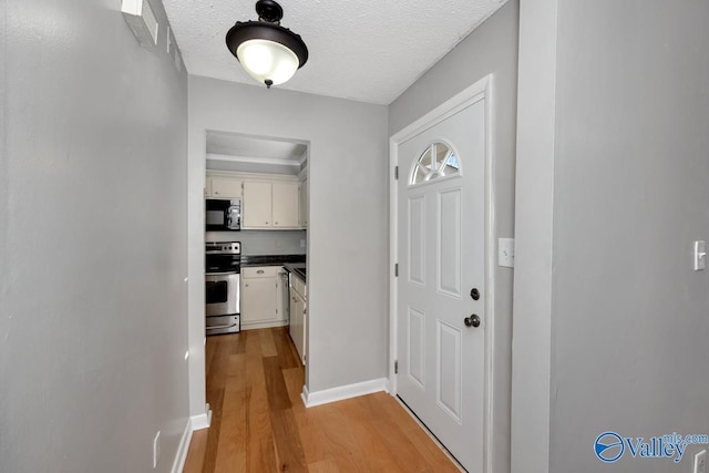 interior space with a textured ceiling and light hardwood / wood-style flooring