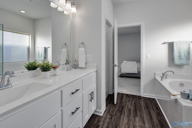 bathroom with dual vanity, a washtub, and wood-type flooring