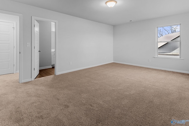 unfurnished bedroom featuring carpet floors, ensuite bath, and baseboards