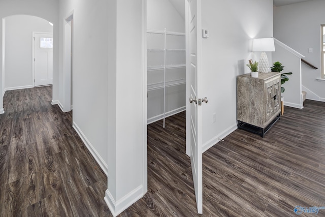 hall with baseboards, stairs, arched walkways, and dark wood finished floors