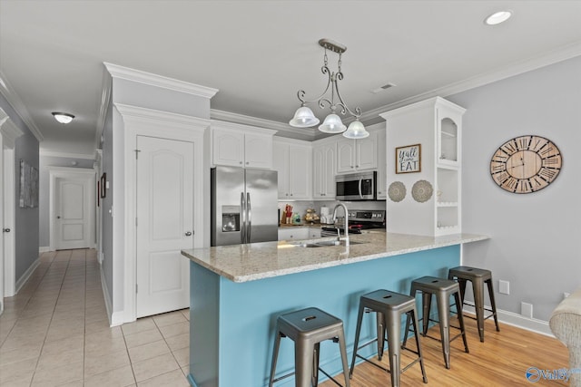 kitchen with sink, appliances with stainless steel finishes, ornamental molding, white cabinets, and kitchen peninsula