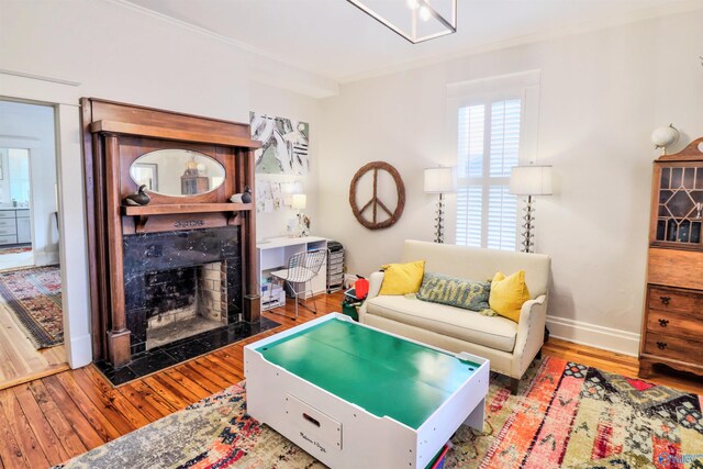living area featuring baseboards, a high end fireplace, crown molding, and hardwood / wood-style flooring