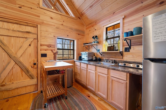 kitchen with lofted ceiling, sink, light hardwood / wood-style flooring, stainless steel fridge, and light brown cabinetry