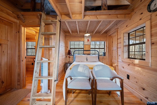 bedroom with wood walls, beamed ceiling, wood ceiling, and light wood-type flooring