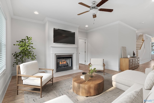 living room with crown molding, light hardwood / wood-style flooring, and ceiling fan