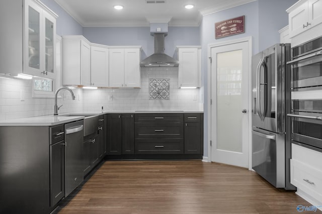 kitchen featuring sink, wall chimney exhaust hood, dark hardwood / wood-style flooring, white cabinets, and appliances with stainless steel finishes