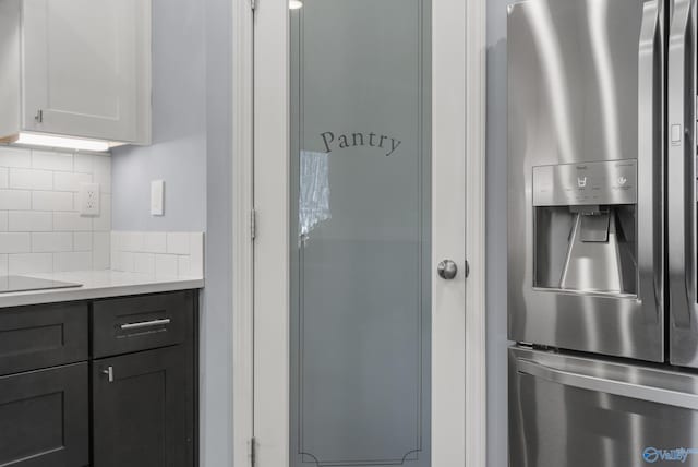 kitchen with white cabinets, stainless steel fridge with ice dispenser, and backsplash