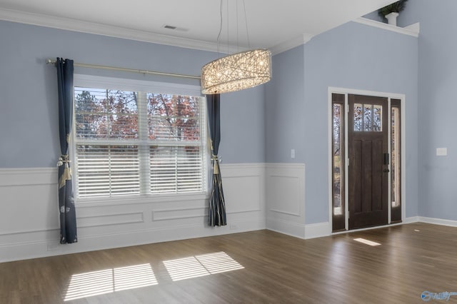 entryway with dark hardwood / wood-style floors, crown molding, and an inviting chandelier