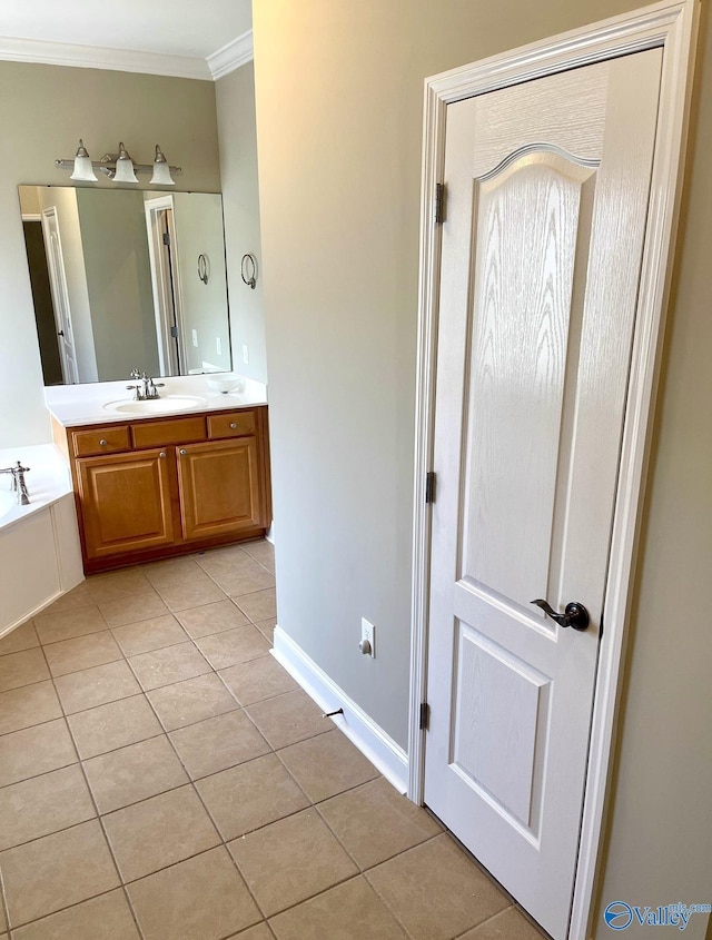 bathroom with tile patterned floors, ornamental molding, a bathing tub, and vanity