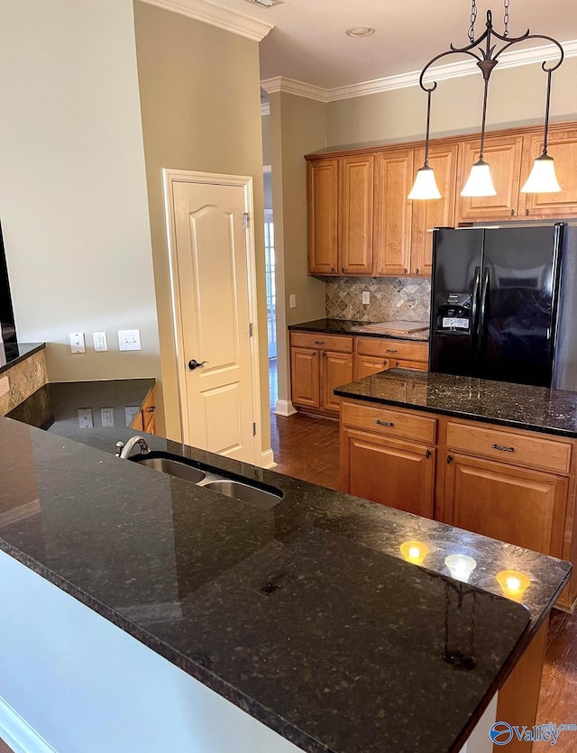 kitchen featuring black fridge, pendant lighting, and dark stone counters