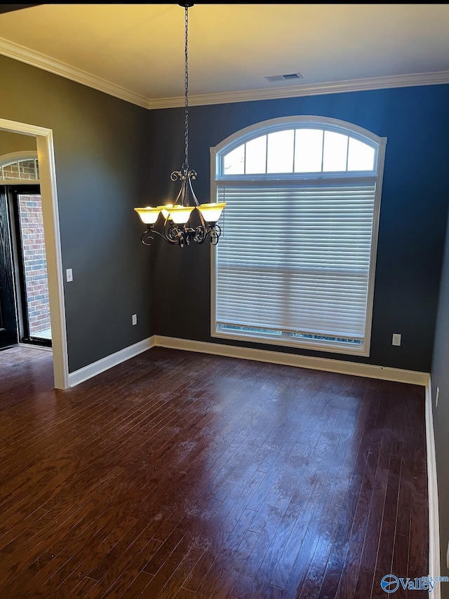 unfurnished dining area featuring crown molding, dark hardwood / wood-style floors, and an inviting chandelier