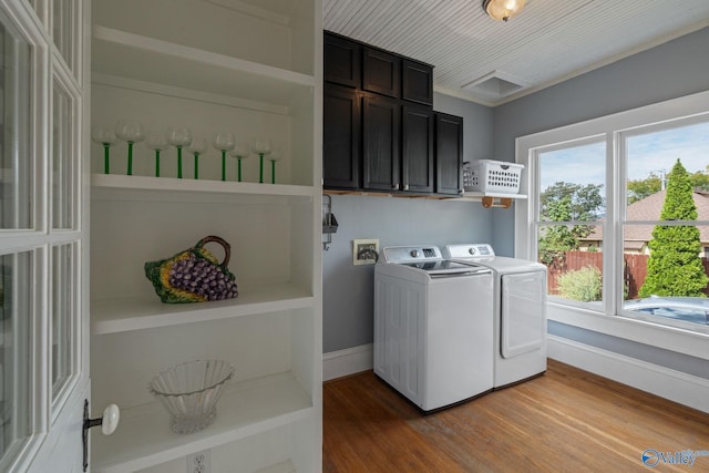 washroom featuring hardwood / wood-style floors, washing machine and dryer, and cabinets