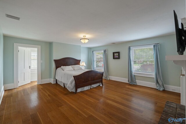 bedroom with multiple windows and hardwood / wood-style floors