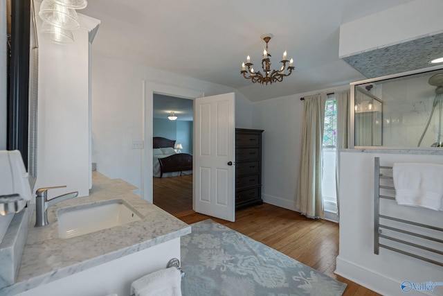 bathroom featuring a shower with door, vanity, hardwood / wood-style floors, and an inviting chandelier