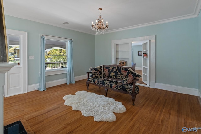 living area with ornamental molding, hardwood / wood-style floors, and a notable chandelier