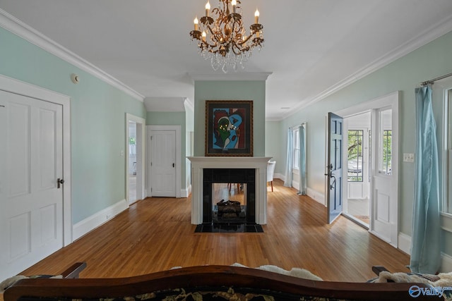 entryway featuring ornamental molding, a multi sided fireplace, hardwood / wood-style flooring, and an inviting chandelier