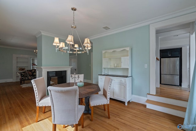 dining space featuring light hardwood / wood-style floors, ornamental molding, and a chandelier