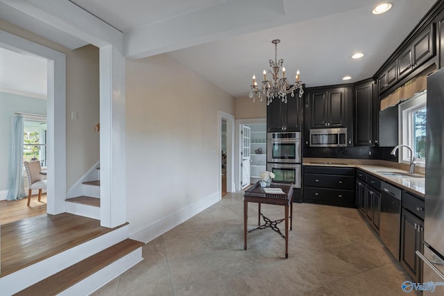 kitchen featuring tasteful backsplash, appliances with stainless steel finishes, a chandelier, sink, and decorative light fixtures