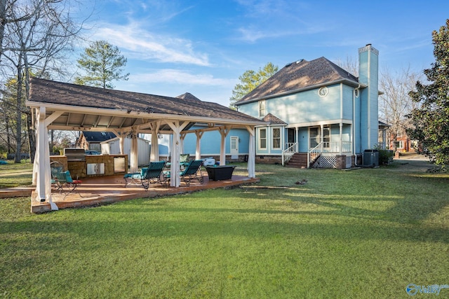 rear view of house featuring central AC unit, a patio area, an outdoor kitchen, and a yard