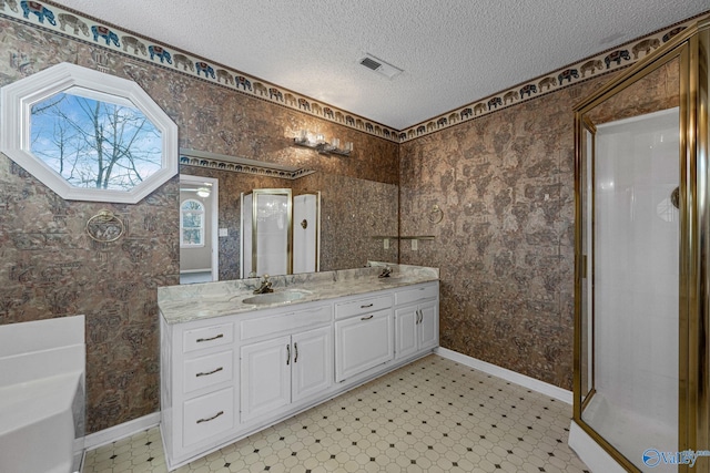 bathroom with a textured ceiling, vanity, and plus walk in shower