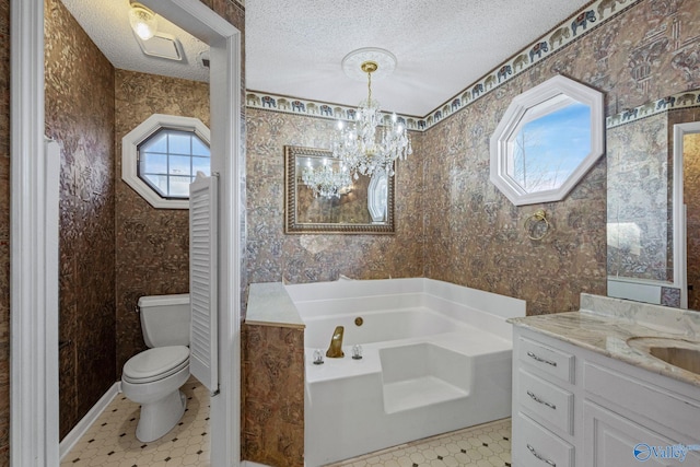 bathroom with toilet, vanity, a tub, an inviting chandelier, and a textured ceiling