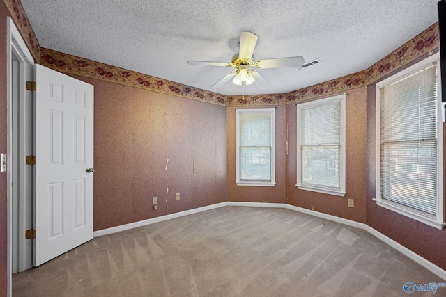 unfurnished room with a textured ceiling, ceiling fan, and carpet floors