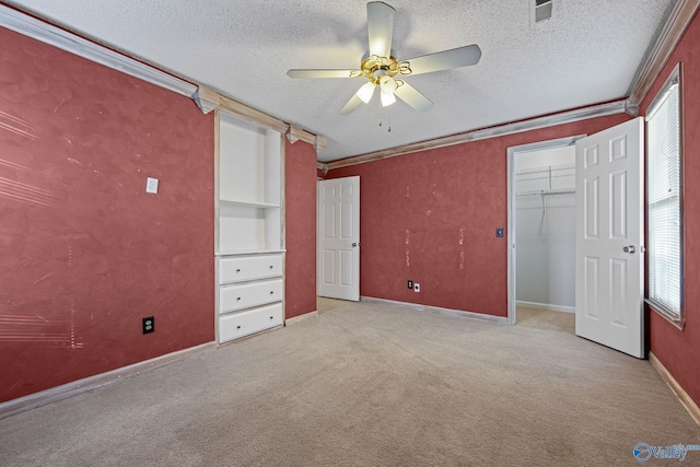 unfurnished bedroom featuring ceiling fan, light carpet, crown molding, and a textured ceiling