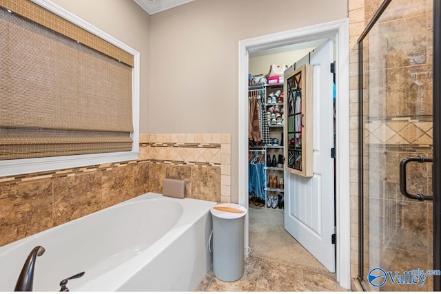 full bath featuring a walk in closet, a garden tub, and a stall shower