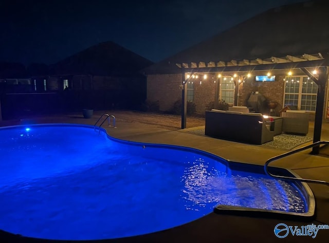 pool at night featuring a patio area and an outdoor pool