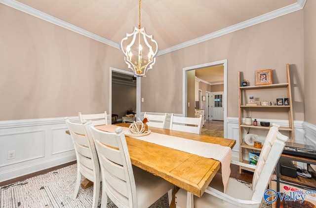 dining room featuring light wood finished floors, a notable chandelier, ornamental molding, and a wainscoted wall