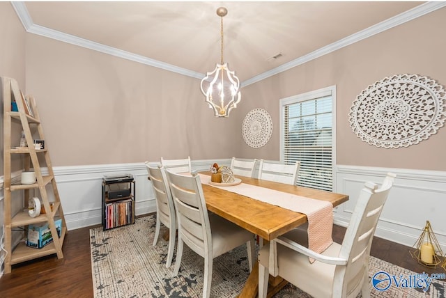 dining space featuring visible vents, ornamental molding, a wainscoted wall, and wood finished floors