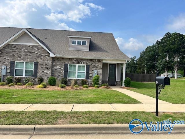 craftsman-style home with fence, a shingled roof, brick siding, and a front yard