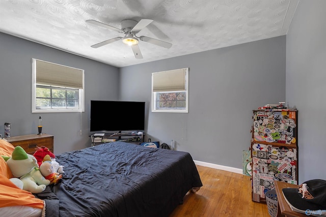 bedroom featuring light wood-style flooring, a ceiling fan, and baseboards
