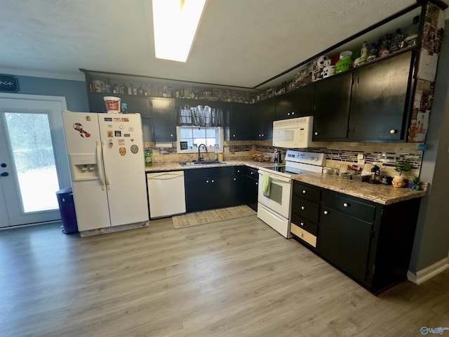 kitchen featuring a sink, light wood-style flooring, white appliances, and dark cabinets