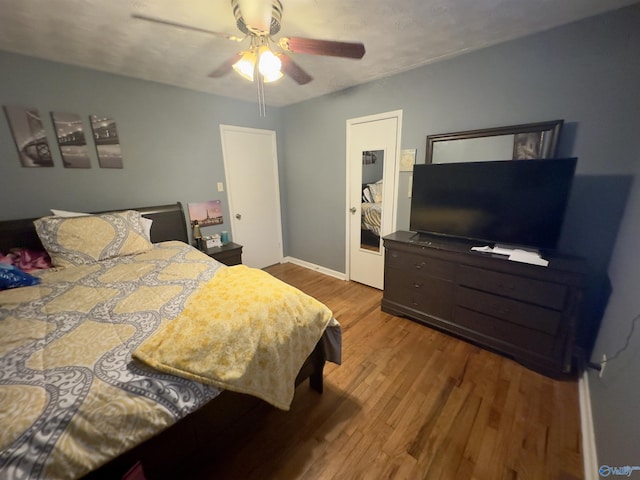 bedroom featuring baseboards, wood finished floors, and a ceiling fan