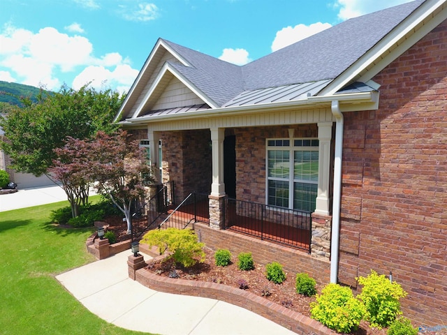 6901 Ridge Pointe Dr SE, Owens Cross Roads, AL 35763 - view of exterior entry featuring a standing seam roof, a shingled roof, a porch, a lawn, and metal roof