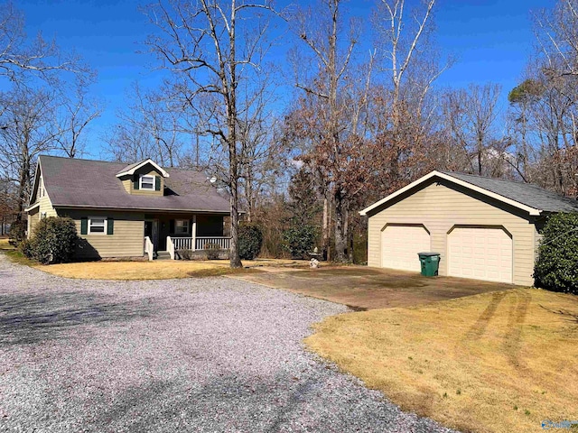 view of side of property with covered porch, a detached garage, an outbuilding, and a yard