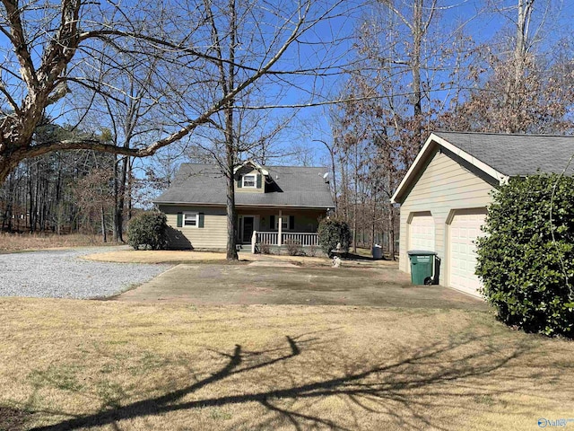 new england style home featuring covered porch, a detached garage, and a front yard