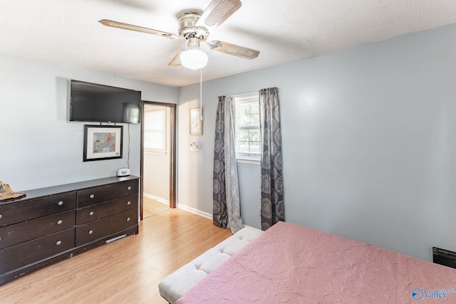 bedroom featuring light wood-type flooring, ceiling fan, and a textured ceiling