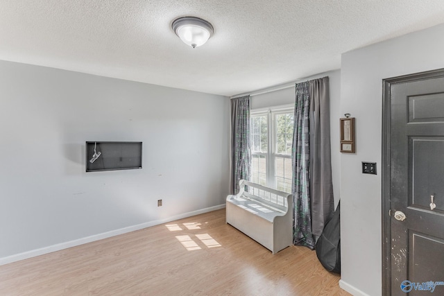 empty room with light hardwood / wood-style floors and a textured ceiling