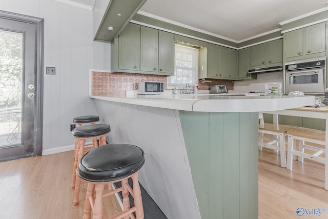 kitchen with oven, a wealth of natural light, a breakfast bar area, and kitchen peninsula