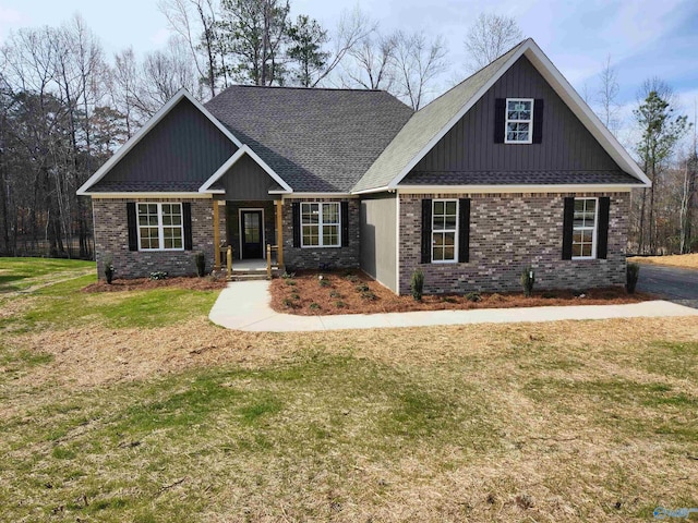 craftsman-style house featuring a shingled roof, a front yard, and brick siding