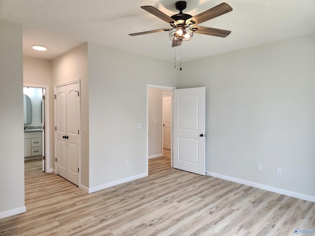 unfurnished bedroom with light wood-type flooring, a ceiling fan, baseboards, and a closet